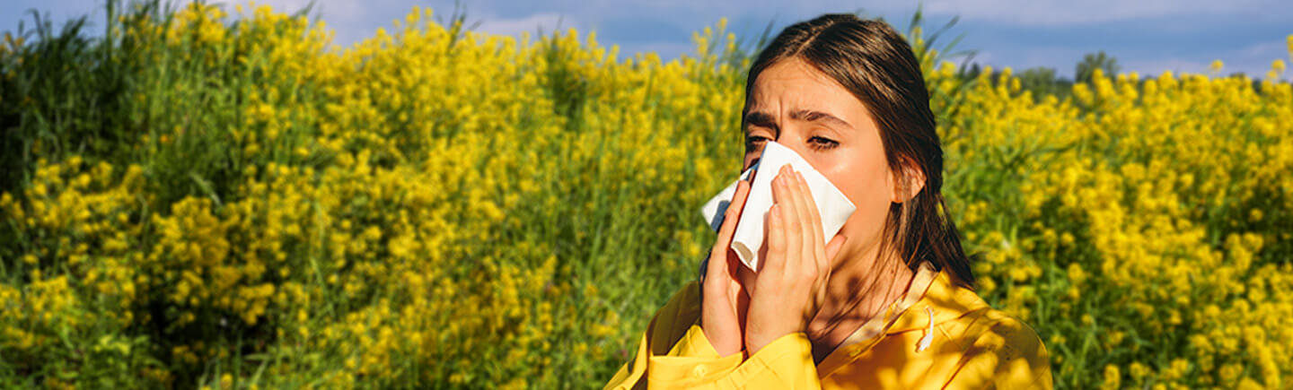 Mujer estornudando debido a la alergia que puede ser producida por la inhalación de polen. - Rhinomer