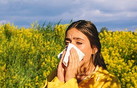 Woman sneezing due to hay fever allergy, which might be produced by pollen inhalation.